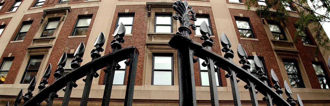 Black ironed gates begin to open in the background is a tall brick building